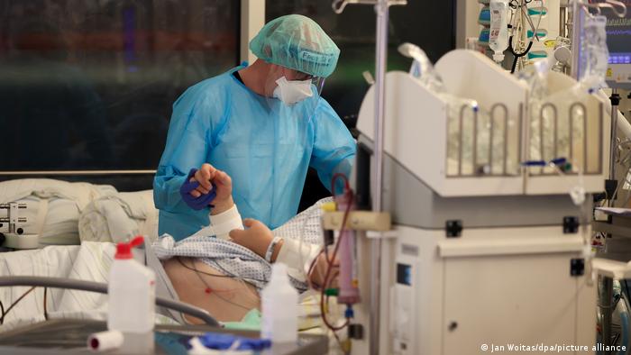 Ein Arzt mit blauer PSA behandelt einen Covit-Patienten auf der Intensivstation