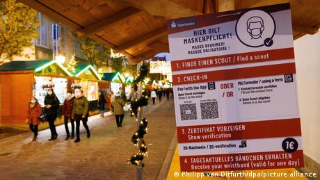 A sign detailing anti-COVID measures on a stall at Freiburg Christmas market.