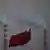 Três bandeiras da China tremulando. Ao fundo, duas grandes chaminés emitem fumaça