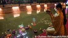 A woman wearing a face mask to prevent the spread of the coronavirus disease (COVID-19), gather to place krathongs (floating baskets) into a canal during the Loy Krathong festival, which is held as a symbolic apology to the goddess of the river in Bangkok, Thailand, November 19, 2021. REUTERS/Chalinee Thirasupa