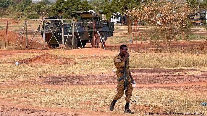 A Burkinabe soldier walks past a French Armoured Personnel Carrier part of a French military convoy heading to Niger, stopped by protesters in Kaya