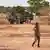 A Burkinabe soldier walks past a French Armoured Personnel Carrier part of a French military convoy heading to Niger, stopped by protesters in Kaya