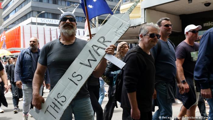 A man holds a sign with the words 'this is war' written on it