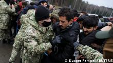 Belarusian servicemen try to control the crowd as migrants jostle to receive food outside the transport and logistics centre near the Belarusian-Polish border in the Grodno region, Belarus November 21, 2021. REUTERS/Kacper Pempel