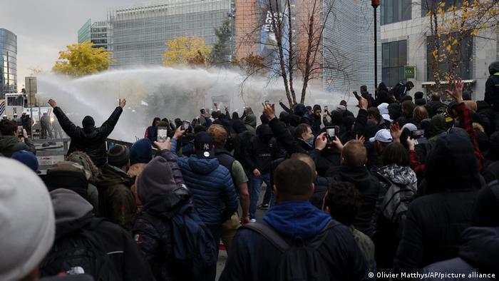 Riot police uses a water canon against protesters in Brussels during a demonstration on Sunday against stricter COVID curbs