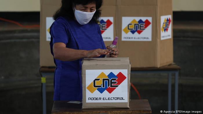 Una mujer ante una urna electoral.