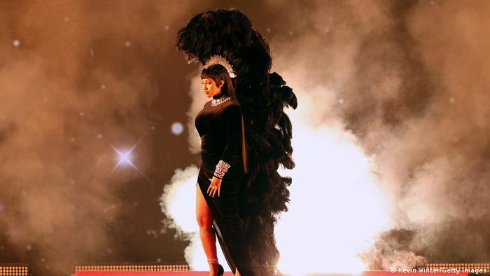 Cardi B in a black gown with feathered hat and feathered back