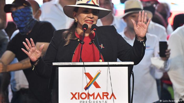 Xiomara delivering a speech in front of a podium with her campaign logo on it.