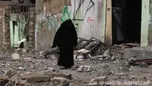 An Iraqi woman makes her way through debris in Mosul's Nablus neighbourhood on March 12, 2017, during an offensive by security forces to retake the western parts of the city from Islamic State (IS) group fighters. (Photo by AHMAD AL-RUBAYE / AFP)