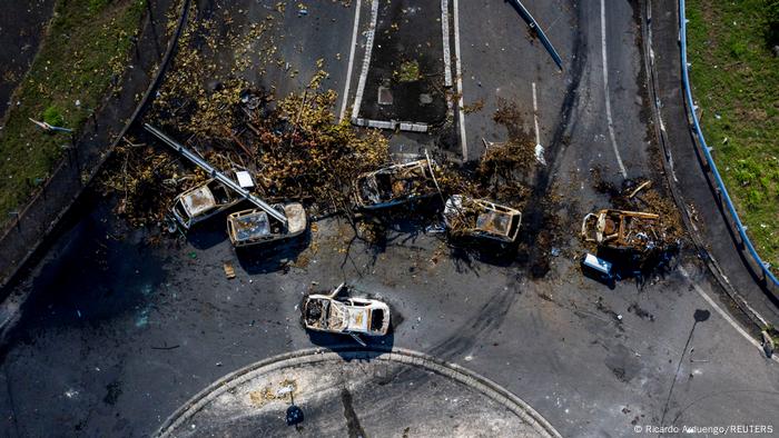 An aerial view of a barricade of burned cars and debris on a round-about blocking traffic 