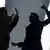 A silhouette of a man hitting a woman