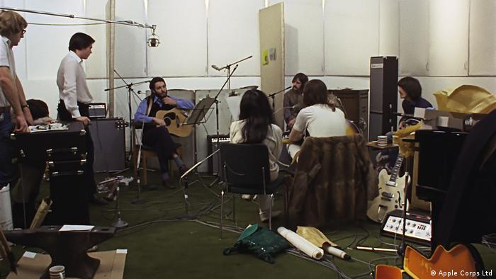 Die Beatles und andere Personen sitzen im im Apple-Studio in der Londoner Savile Row und besprechen etwas