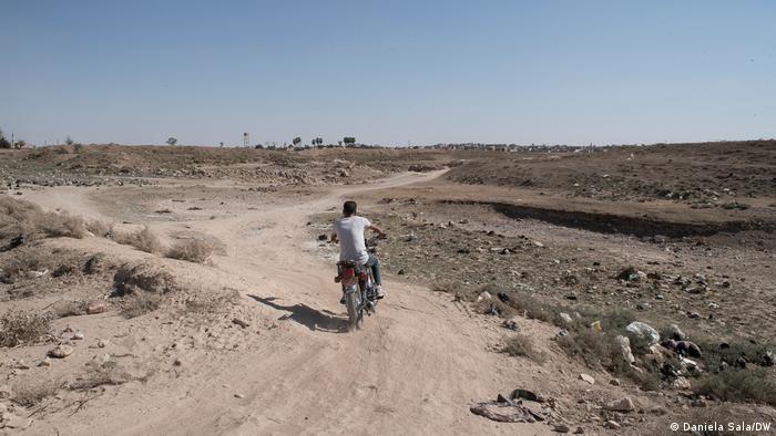 A motorcycle rides through an empty riverbed 