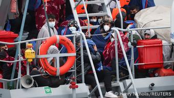 Migrants onboard a Border Force rescue boat wait to disembark at Dover harbour