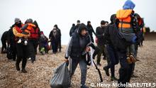 Migrants walk along a beach after being brought ashore by a RNLI Lifeboat, after having crossed the channel, in Dungeness, Britain, November 24, 2021. REUTERS/Henry Nicholls 