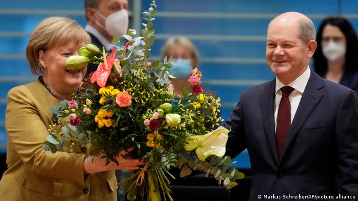 Olaf Scholz (kanan) memberi bunga kepada Kanselir Angela Merkel dalam rapat kabinet Merkel yang terakhir, 24 November 2021