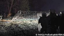 Polish law enforcement officers stand guard near a damaged fence on the Polish-Belarusian border near the settlement of Starzyna, Poland, in this image released by the Polish Police November 24, 2021. Policja Podlaska/Handout via REUTERS ATTENTION EDITORS - THIS IMAGE HAS BEEN SUPPLIED BY A THIRD PARTY. NO RESALES. NO ARCHIVES. MANDATORY CREDIT. 