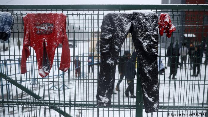 Clothes hang on a fence at a transport and logistics center, covered in snow