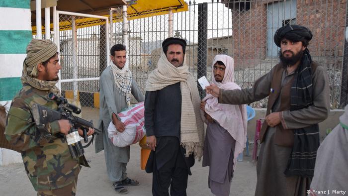The Taliban check ID cards of people at the Angoor Ada crossing