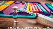 Covid-19 Impfung für Kinder in der Schule und im Kindergarten, Impfpflicht Präsents Unterricht und 2G Regel für Schüler und Studenten, Spritze mit Impfdosis mit Schülermäppchen