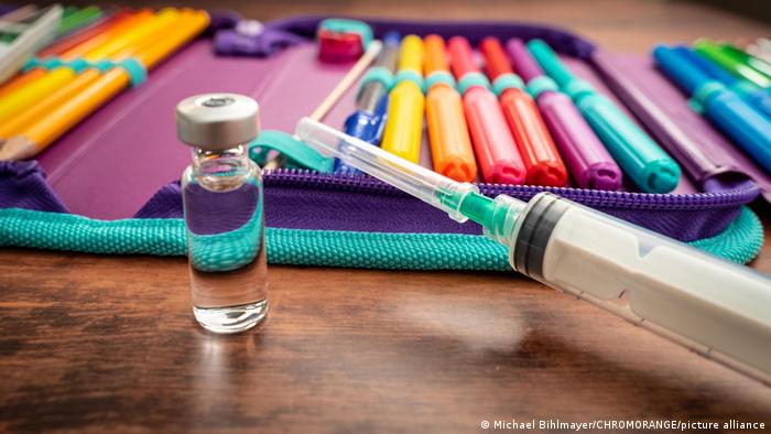 A pencil case alongside a syringe and a vaccine dosis