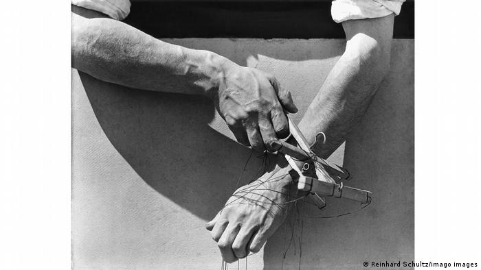 A photo of a Mexican puppeteer's hands holding puppeteer strings.