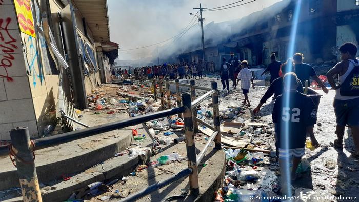 People walk through the looted streets of Chinatown in Honiara, Solomon Islands