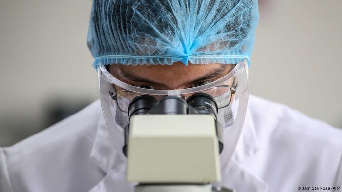 A medical technology student wearing protective gear looks through a microscope in Manila