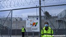 Employees stand outside the new closed migrant camp in the Greek island of Kos on November 27, 2021. - Greece on November 27, 2021 opened two more of its new closed migrant camps that have been criticised by rights groups for their restrictive measures. The closed camps feature barbed wire fencing, surveillance cameras, x-ray scanners and magnetic doors and gates remain closed at night. (Photo by ARIS MESSINIS / AFP)