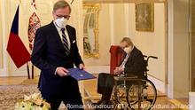 Czech President Milos Zeman, right, in a transparent cube because he tested positive to COVID-19, appoints ODS leader Petr Fiala, left, as Czech Prime Minister at the Lany manor, near Prague, Sunday, Nov. 28, 2021. The Czech president has sworn in Petr Fiala as the country’s new prime minister following last month’s parliamentary election. Milos Zeman and Fiala, the leader of the coalition that captured most votes in the Oct 8-9 vote were separated by a clear screen during the ceremony at the presidential chateau in Lany, west of Prague, after the president tested positive for the coronavirus and must isolate. (Roman Vondrous/CTK via AP)
