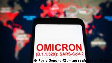 November 26, 2021, Ukraine: In this photo illustration, words that say Omicron (B.1.1.529): SARS-CoV-2 is seen on a mobile phone screen in front of the COVID-19 Map of Johns Hopkins Coronavirus Resource Center in the background. (Credit Image: © Pavlo Gonchar/SOPA Images via ZUMA Press Wire