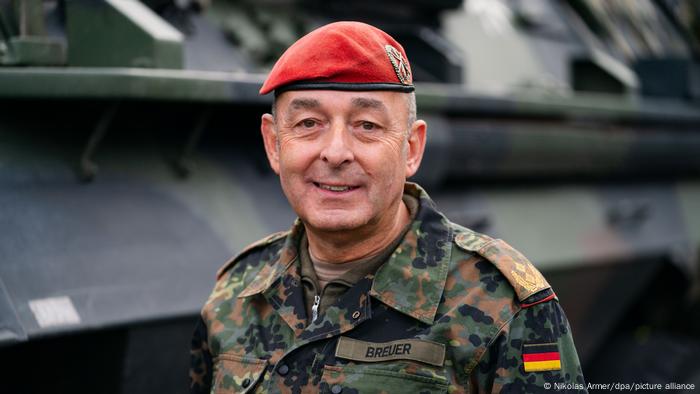 Carsten Brewer in Uniform steht vor einem gepanzerten Fahrzeug