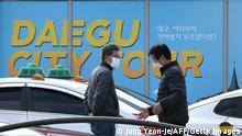 Taxi drivers wearing protective face masks, as a preventative measure against the COVID-19 coronavirus, chat as they wait for passengers in front of Dongdaegu railway station in Daegu, on February 26, 2020. - An American soldier stationed in South Korea has tested positive for the novel coronavirus, commanders said on February 26, as the country's case total jumped again. Meanwhile, South Korean authorities reported 169 new infections, taking the overall national tally to 1,146, by far the largest outside China. (Photo by Jung Yeon-je / AFP) (Photo by JUNG YEON-JE/AFP via Getty Images)