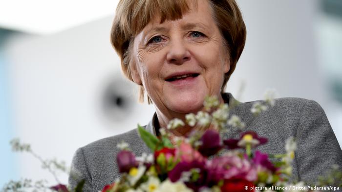 Angela Merkel holding a bunch of flowers, smiling