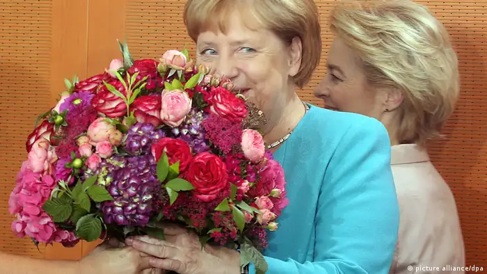 Former Chancellor Angela Merkel receiving a bouquet of flowers.