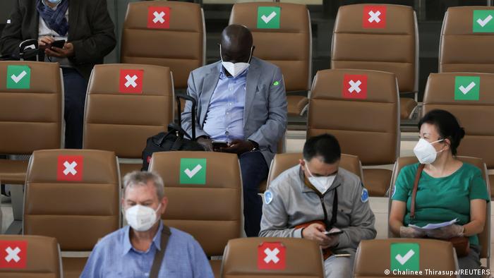 People with masks seated on chairs in Bangkok's International Airport