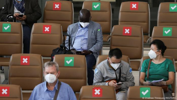 People with masks seated on chairs in Bangkok's International Airport