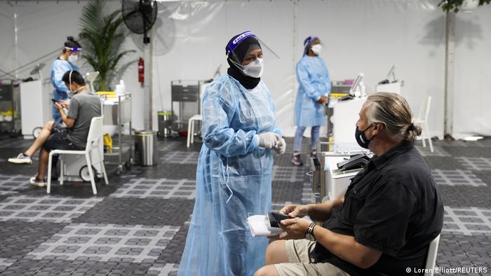 A woman in PPE suit and mask speaks to a man at a testing center at Sydney Airport in Australia
