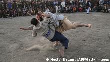 Afghan men wrestle as spectators watch in the background during a weekly spectacle of wrestling held in a makeshift arena at Chaman-e-Hozori park, in Kabul City, on November 12 2021. (Photo by Hector RETAMAL / AFP) (Photo by HECTOR RETAMAL/AFP via Getty Images)