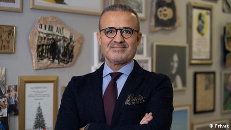 TOBB Hazır Giyim ve Konfeksiyon Sektör Meclis Başkanı Şeref Fayat takım elbise giymiş, gözlük takıyor ve ellerini birbirine bağlayarak kameraya poz veriyor TOBB Hazır Giyim ve Konfeksiyon Sektör Meclis Başkanı Şeref Fayat takım elbise giymiş, gözlük takıyor ve ellerini birbirine bağlayarak kameraya poz veriyor