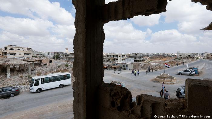A picture taken during a tour organized by the Syrian Ministry of Information shows people and journalists at a damaged roundabout in the district of Daraa al-Balad of Syria's southern city of Daraa, on September 12, 2021.