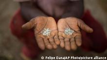 In this Nov. 19, 2015 photo, an artisanal miner shows the diamonds he and his group found in an abandoned mine in Areinha, Minas Gerais state, Brazil. The area has been explored for the precious stone since the time of slavery, and up to a couple of years ago, multinational mining companies extracted the stone without care for the land or the Jequitinhonha river that crosses the region. (AP Photo/Felipe Dana)