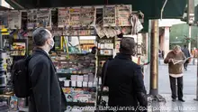 Menschen lesen Zeitungen in einem Kiosk in der Nähe des Omonia-Platzes in Athen.