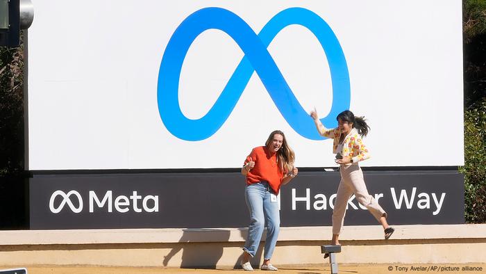 Facebook-Angestellte vor dem neuen Firmen-Logo Meta