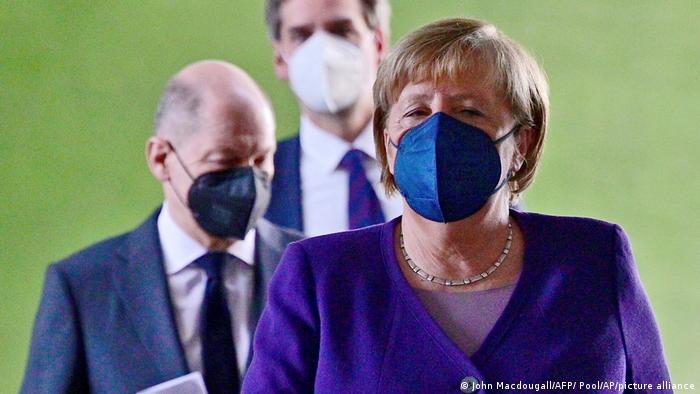German Chancellor Angela Merkel, followed by Olaf Scholz, left, arrive for a press conference following a meeting with the heads of government
