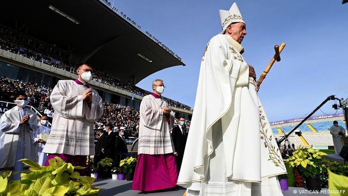 Pope Francis holds a wooden cross during a mass at a sports stadium