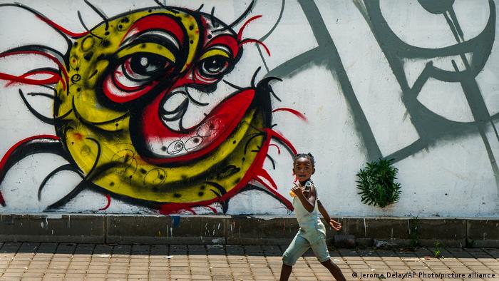 A child walks past a COVID artwork in Soweto, Johannesburg, South Africa
