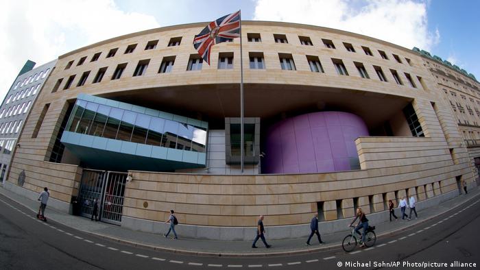 The Union Jack waves at the the British embassy in Berlin as people walk past on the street below