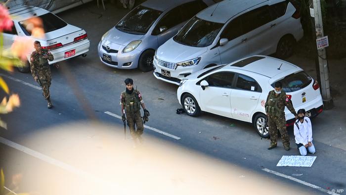 Seorang pengunjuk rasa, yang mengambil bagian dalam demonstrasi menentang kudeta militer, berlutut di tanah di samping seorang tentara setelah ditahan Seorang pengunjuk rasa, yang mengambil bagian dalam demonstrasi menentang kudeta militer, berlutut di tanah di samping seorang tentara setelah ditahan