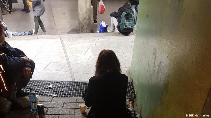 Бездомная женщина сидит на ступеньках 